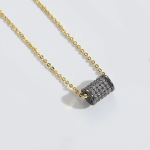 Close-up of gold chain with black cylindrical pendant pavé set with sparkling zircon