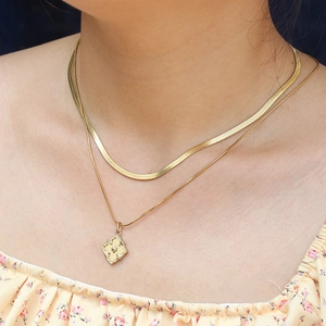 Close-up of double layered 18k gold plated herringbone chain with hollow flower pendant