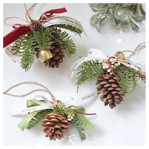 Close-up of pine cone ornaments with festive ribbons and bells on white background