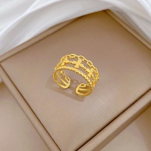 Vue détaillée de la bague trèfle dorée ajustable dans un coffret à bijoux beige doux