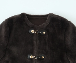 Detail of dark brown faux fur jacket with black leather trim and gold metal buckles