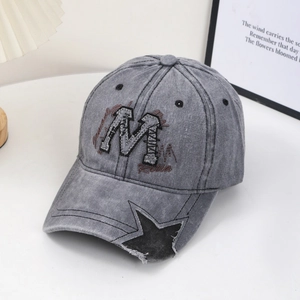 Detail of gray washed baseball cap with embroidered M patch and star cutout on the brim