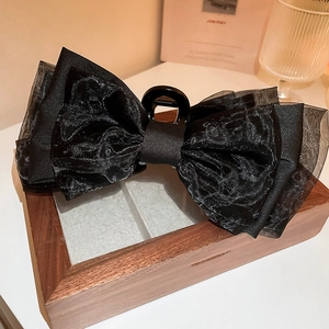 Détail d'une grande pince à cheveux en organza noir avec double nœud élégant et raffiné