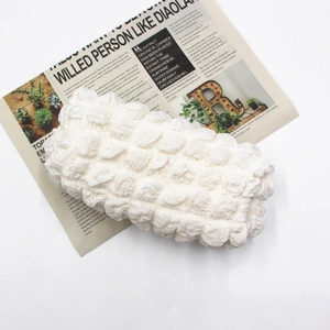 Top view of a white bubble texture makeup bag on white background with newspaper decor