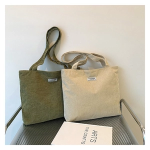 Detail view of large corduroy tote bags in olive green and beige on a metal chair