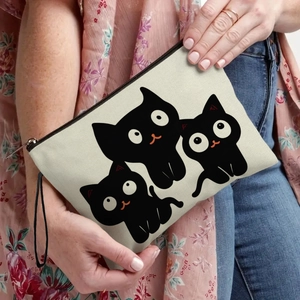 Cute cartoon cat canvas cosmetic bag with black zipper and wrist strap held by hand