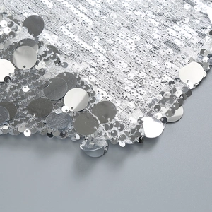Macro detail of silver sequins on mesh fabric showing premium craftsmanship and metallic texture