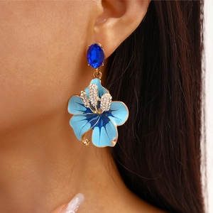 Dettaglio degli orecchini a fiore in smalto blu con strass indossati dalla modella