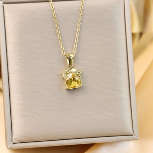 Gros plan du pendentif patte de chat doré avec zircon en cœur jaune dans un coffret