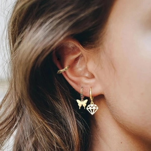 Close-up of gold butterfly earring with colorful crystals and geometric diamond pendant