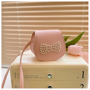 Mini sac bandoulière rose avec nœud en perles sur un meuble élégant avec tulipes