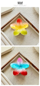 Detail view of colorful gradient plumeria hair claws in resin on a linen tray