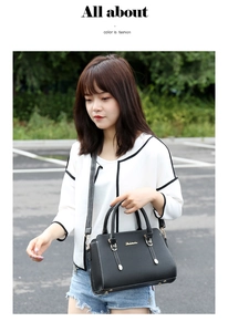 Close-up of black crossbody bag with golden logo and adjustable strap worn by a model