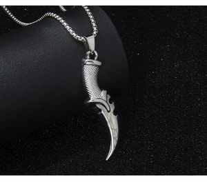 Macro shot of silver punk scythe pendant with detailed engravings and metallic texture
