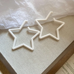 Détail de boucles d'oreilles en forme d'étoile sur fond lin montrant texture et éclat