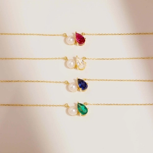 Detailed view of teardrop gemstones and pearls on fine gold chains in four colors