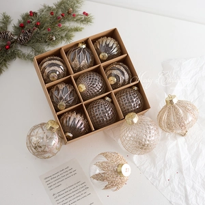 Set of 12 transparent champagne gold Christmas tree ornaments with varied patterns in a kraft box