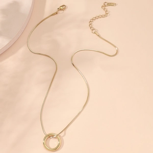 Gros plan d'un collier en acier inoxydable doré avec pendentif rond sur fond chaud
