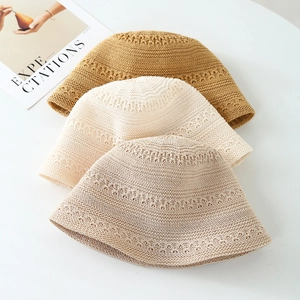 Close-up of three hand-knitted wool bucket hats in brown and cream stacked on a table