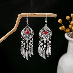 Vue détaillée de boucles d'oreilles bohèmes argentées avec perles rouges et plumes