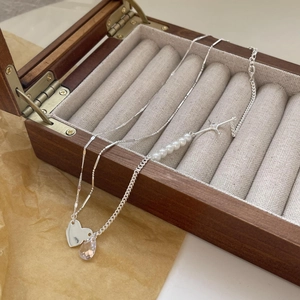 Detail of silver heart and pearl necklaces on a vintage wooden jewelry box