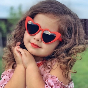 Enfant portant des lunettes de soleil rouges en forme de cœur avec verres de protection UV