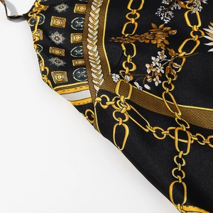 Détail d'imprimé baroque sur tissu soyeux avec motifs dorés et fleurs blanches