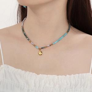 Detail of beaded necklace with gold shell pendant on model for a vintage boho look