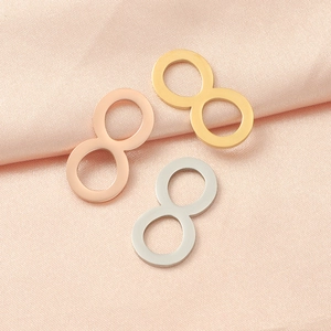 Three infinity symbol charms in gold, rose gold and silver on pink silk fabric