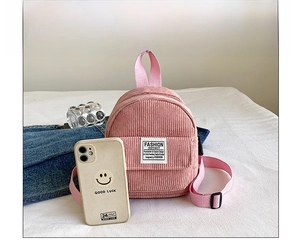 Pink corduroy mini backpack pouch next to a smartphone for product size comparison
