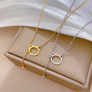 Close-up of titanium steel cat pendant necklaces in gold and silver on silk fabric