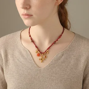 Ethnic braided red rope necklace with red agate, wood beads, and a gold cross pendant