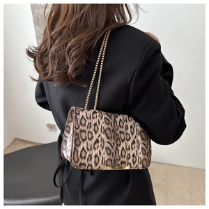 Borsa a tracolla leopardata alla moda con catena dorata su una giacca nera elegante