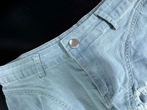 Dettagli degli shorts in denim azzurro a vita alta con bottone in metallo argento e zip