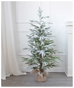 Detail of a frosted faux Christmas tree with snow-covered needles and a rustic burlap base