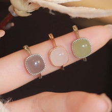 Close-up of three square gemstone rings in lilac, pink, and green with beaded edges