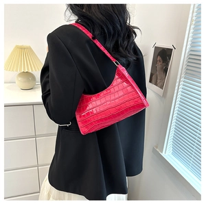 Detail of vibrant magenta crocodile texture shoulder bag styled with a minimalist outfit