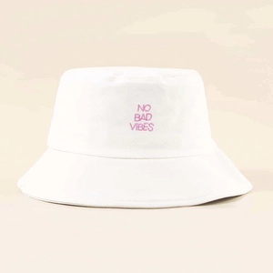 White cotton bucket hat with pink No Bad Vibes embroidery on a minimal beige background