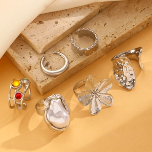 Detail of silver rings set featuring baroque pearls and flower motifs on stone background
