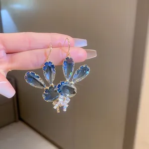 Close-up of deep blue crystal teardrop earrings featuring a delicate pavé butterfly
