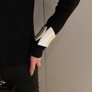 Detail of wide irregular silver cuff bracelet with a brushed matte finish on a black sleeve