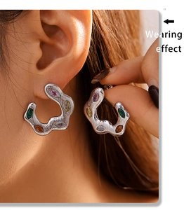 Close-up of model wearing C-shaped silver earrings with colorful zircon inlay