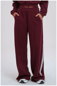 Detail of dark burgundy sports trousers featuring white side stripes and front pleats