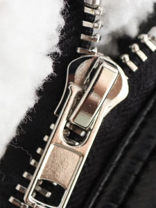 Detail of silver double zipper on black biker jacket with soft white faux fur lining