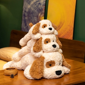 Three sizes of soft plush puppy dog toys stacked together on a wooden table.