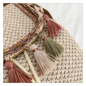 Detail of handmade straw bucket bag with multi-color cotton tassels and woven strap texture