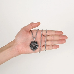 Detailed close-up of a silver wolf head pendant and twisted chain held in hand