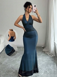 Close-up of deep teal halter evening gown with sheer black mesh hem and backless detail