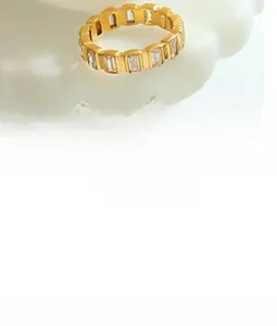 Dettaglio di un anello dorato con zirconi taglio baguette su un vassoio decorativo