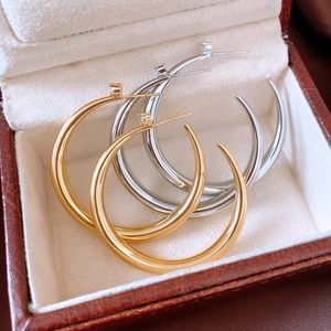 Detailed macro view of 18k gold and silver geometric hoop earrings in a jewelry box